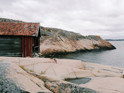 A red timber boathouse on the rocks of the Swedish coast